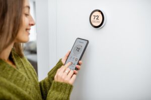 woman-adjusting-thermostat-with-smartphone-app